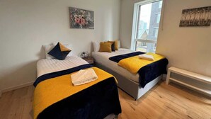 Een slaapkamer met twee bedden, een raam en kunstwerken aan de muur.