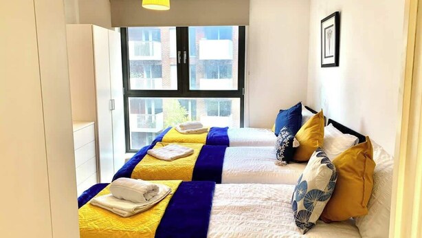 Ein Hotelzimmer mit zwei Betten, einem großen Fenster und einer gelben Pendelleuchte.