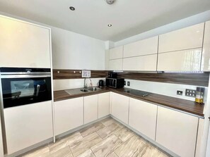 Eine moderne Küche mit weißen Schränken, einem schwarzen Backofen, einer Mikrowelle und einer Holzarbeitsplatte.