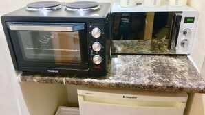A kitchen with a black toaster oven, a microwave, and a coffee maker on the counter. - En-suite Studio Room with Kitchenette, Parking (Greater London)