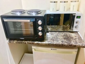 A kitchen with a black toaster oven, a microwave, and a coffee maker on the counter. - En-suite Studio Room with Kitchenette, Parking (Greater London)