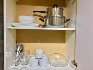 A kitchen with a pot, plates, cups, and a bowl on shelves. - En-suite Studio Room with Kitchenette, Parking (Greater London)
