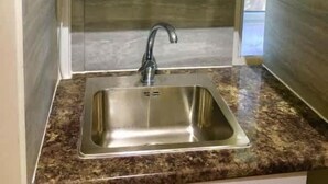 A kitchen with a stainless steel sink, a pot on the shelf, and glassware. - En-suite Studio Room with Kitchenette, Parking (Greater London)