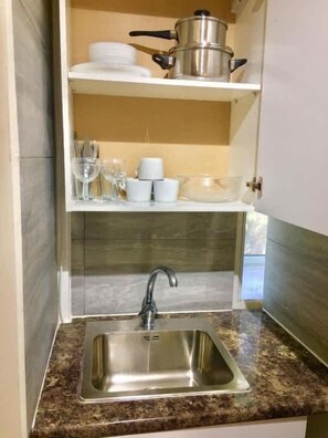 A kitchen with a stainless steel sink, a pot on the shelf, and glassware. - En-suite Studio Room with Kitchenette, Parking (Greater London)