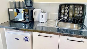 A compact kitchen with a coffee maker, toaster, kettle, and a dishwasher. - Studio flat en-suite, Kitchenette, Parking, NP7 (Newbury Park)