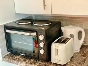 Eine Küche mit einem schwarzen Toastern, einem weißen Toaster und einem weißen Wasserkocher auf einer Granit Arbeitsplatte.