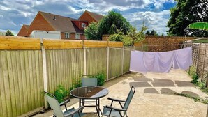 A backyard patio with a round table and four chairs, a wooden fence, and a brick wall.