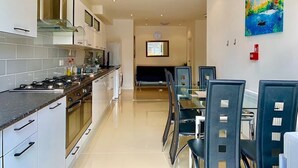 A modern kitchen with a dining area, a large window, and a painting on the wall.