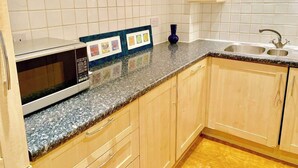 Una cucina con forno a microonde, lavello e mobili in legno.