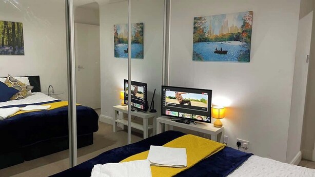 Una camera d'albergo con un letto, una TV, una scrivania e uno specchio.