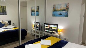 Een hotelkamer met een bed, een televisie, een bureau en een spiegel.