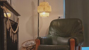 Een leren fauteuil in een kamer met een geweven lamp en een klein geweven mandje.