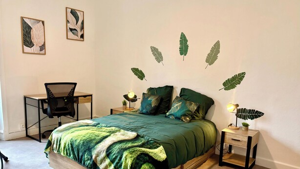 Een slaapkamer met een bed, bureau, stoel en nachtkastjes.