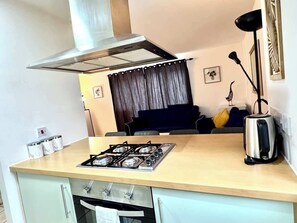 A compact kitchen with a gas stove, a toaster, and a kettle.