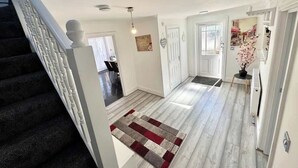 Ein modernes Interieur mit einer Treppe, einem Flur mit einem gemusterten Teppich und einer Tür zu einem weiteren Raum.