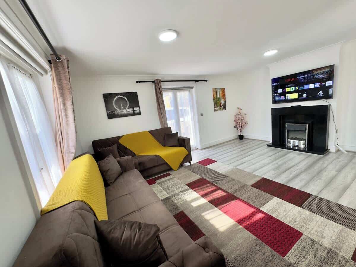 Una sala de estar con sofá, chimenea, televisor y ventana con cortinas.