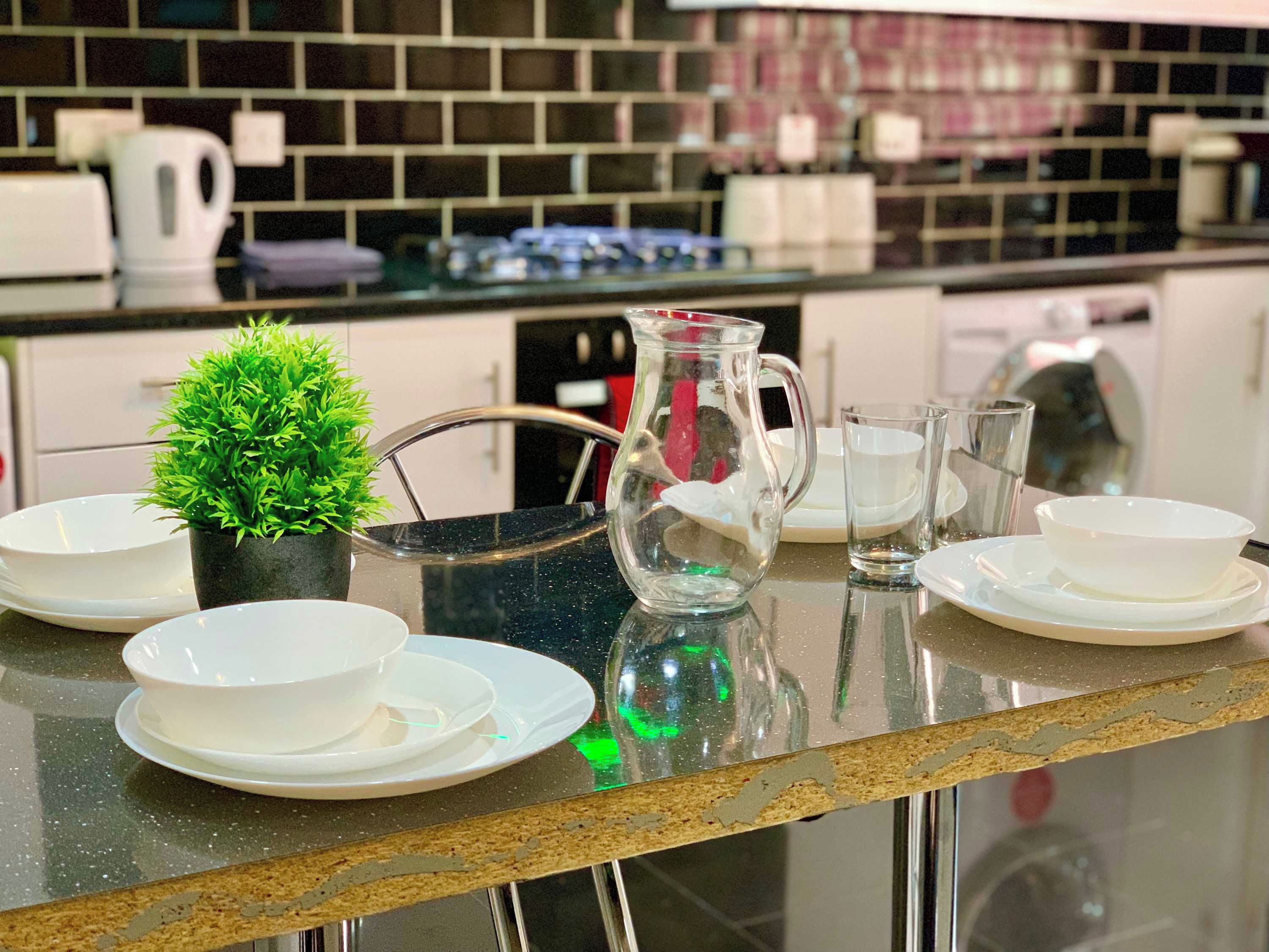 A kitchen counter with a coffee maker, a glass pitcher, and a small potted plant.