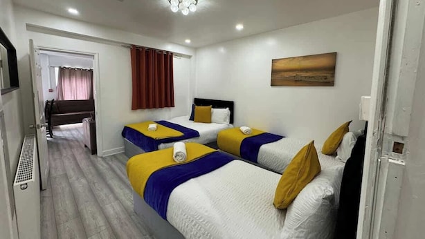 Habitación de hotel con tres camas, un cuadro en la pared y una lámpara en el techo.