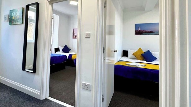 Een hotelkamer met twee bedden, een spiegel en een schilderij aan de muur.