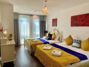 Ein Hotelzimmer mit zwei Betten, einem Schreibtisch und einem großen Fenster mit Vorhängen.