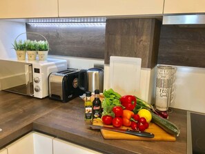 Eine Küche mit Toaster, Wasserkocher und frischem Gemüse auf der Arbeitsfläche.