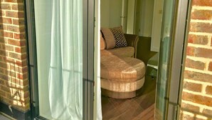 Een kamer met een bakstenen muur, een schuifdeur van glas en een bank met decoratieve kussens.
