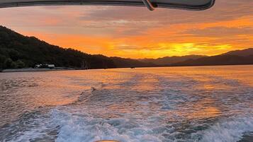 Un bateau naviguant sur une étendue d’eau, avec un coucher de soleil en arrière-plan.