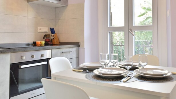 A modern kitchen with a dining area, featuring a large window, a built-in oven, and a dining table set for four. - Cozy and bright 60 square meters apartment, perfect for four people, located on the first floor of a renovated building without an elevator.The property is located in a quiet area in the Crocetta neighborhood and is well connected to the rest of the city (Turin)