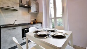 A modern kitchen with a dining table set for four, a built-in oven, and a window with a view. - Cozy and bright 60 square meters apartment, perfect for four people, located on the first floor of a renovated building without an elevator.The property is located in a quiet area in the Crocetta neighborhood and is well connected to the rest of the city (Turin)
