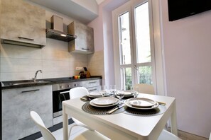 A modern kitchen with a dining table set for four, a built-in oven, and a window with a view. - Cozy and bright 60 square meters apartment, perfect for four people, located on the first floor of a renovated building without an elevator.The property is located in a quiet area in the Crocetta neighborhood and is well connected to the rest of the city (Turin)