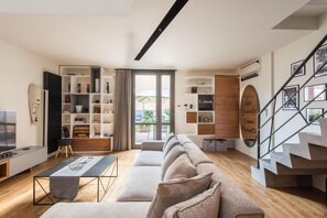 Een moderne woonkamer met een bank, een televisie, een boekenkast en een trap.