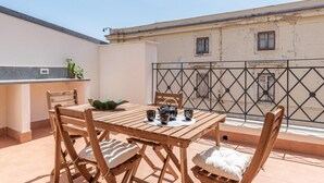 Une table en bois, des chaises et un petit coin cuisine équipé d’un évier et d’un plan de travail.