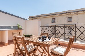 A wooden table with chairs and a small kitchen area with a sink and countertop. - Oretea apartment (PALERMO)