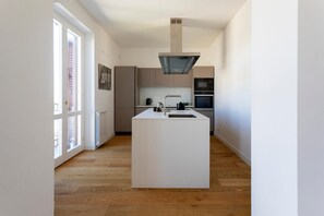A modern kitchen with a central island, built-in appliances, and large windows. - Oretea apartment (PALERMO)