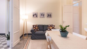 Un soggiorno con un divano grigio, un tavolino, una lampada e tre opere d'arte appese al muro.