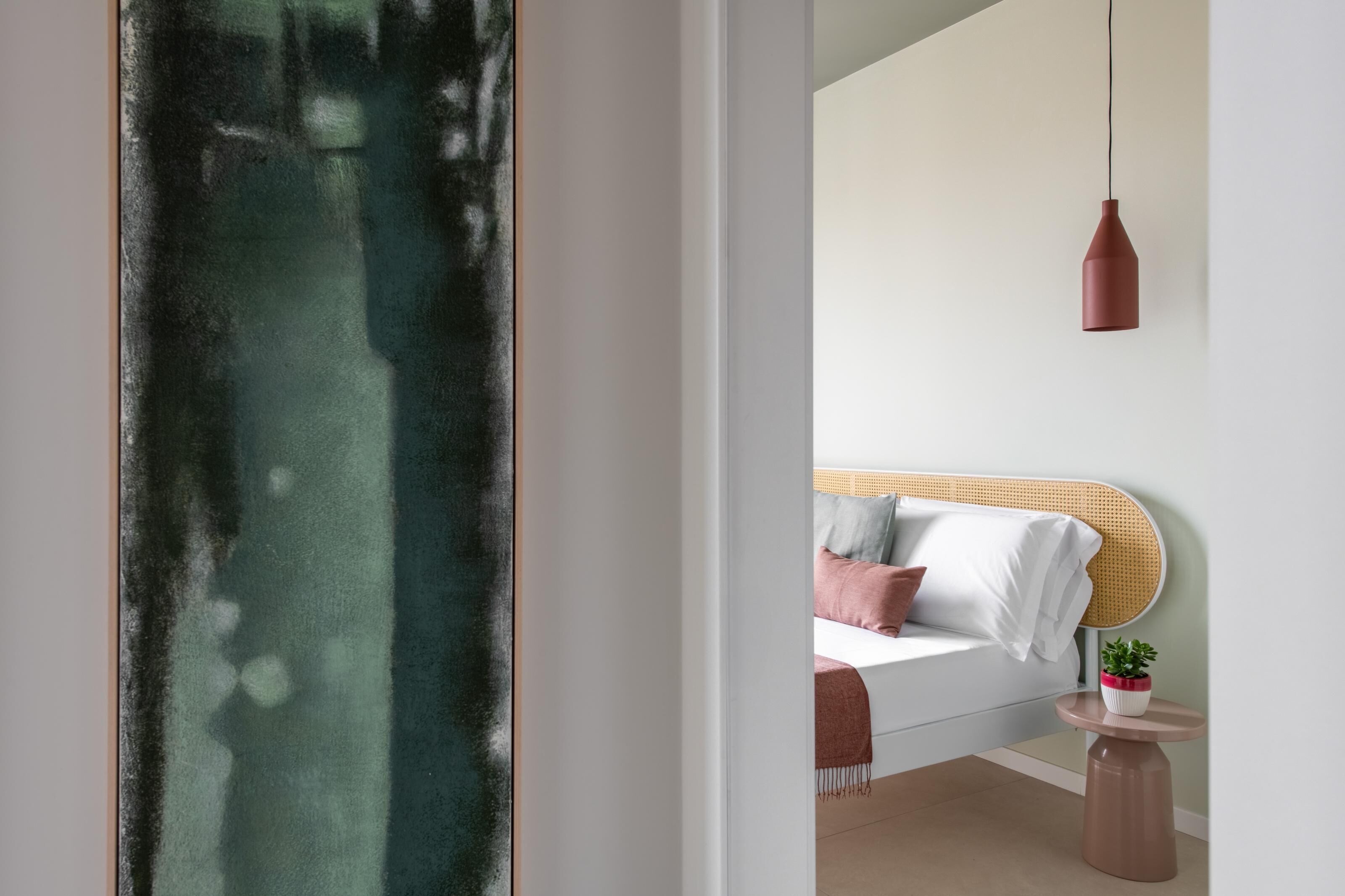 A modern bedroom with a bed, bedside table, and a hanging pendant light.