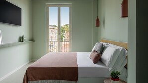 Ein Schlafzimmer mit einem Bett, einem Fernseher, einem Balkon und einer Topfpflanze.