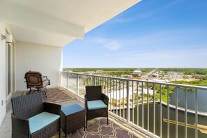 A balcony with wicker furniture and a view of a river and buildings. - Treasured Memories at Laketown Wharf 1430 (Panama City Beach)
