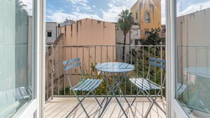 Un balcone con una porta vetrata, un tavolino rotondo e due sedie blu.
