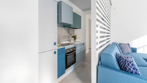 Una cucina moderna con elettrodomestici integrati, un divano blu con cuscini a motivi e una ringhiera bianca.