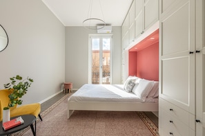 A bedroom with a bed, a chair, a small table, a potted plant, and a view of the outside. - Parlatore design apartment (PALERMO)