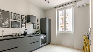 Eine moderne Küche mit grauen Schränken, einer schwarzen Arbeitsplatte und einem Fenster mit Blick auf einen Balkon.