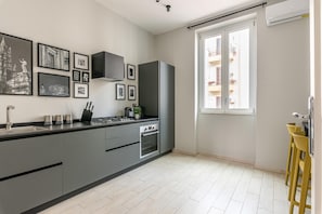 A modern kitchen with grey cabinets, a black countertop, and a window with a view of a balcony. - Parlatore design apartment (PALERMO)