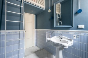 Ein Badezimmer mit einem weißen Waschbecken, einem Spiegel, einem Handtuchhalter und einer Tür.