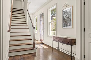 Eine Treppe mit Holzboden und Handlauf, ein Holztischchen mit Schubladen und ein gerahmtes Bild an der Wand.