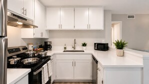 Una cucina moderna con mobili bianchi, un piano cottura nero, un forno a microonde e un lavello.