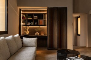 A modern living room with a sofa, a coffee table, and a bookshelf with decorative items. - ASTRA PENTHOUSE (Bologna)