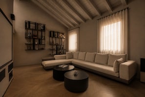 A modern living room with a sectional sofa, two round coffee tables, and built-in shelving with decorative items. - ASTRA PENTHOUSE (Bologna)