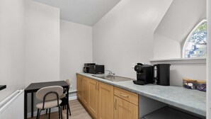 Una cocina compacta con una mesa y sillas, una cafetera, un hervidor y una ventana con vistas.