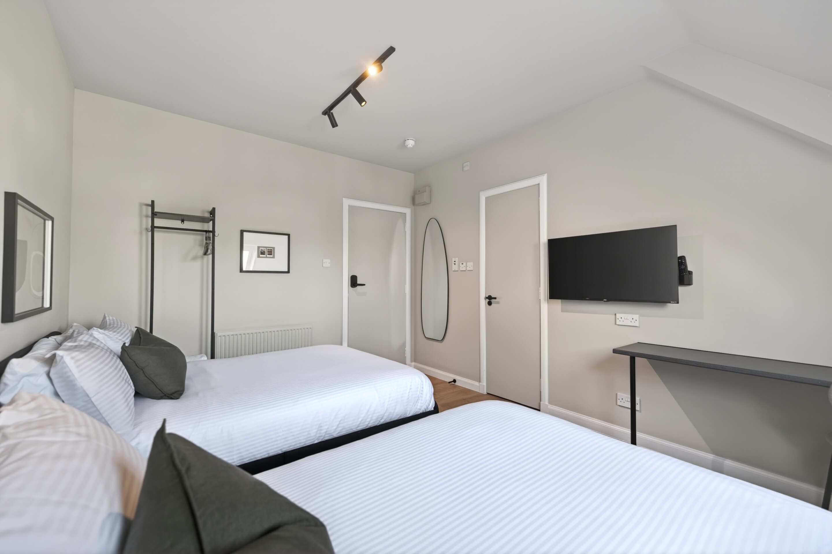 Une chambre d’hôtel avec deux lits, un téléviseur fixé au mur et une petite table.